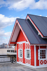 Fragment of a red wooden house with a gray roof against the blue sky