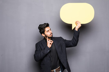 Young indian business man holding a bubble for text, isolated on a grey background