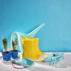 the Yellow rubber boots on the white wooden table on the blue background. Garden accessories.
