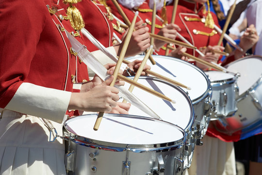 Closeup of group of girls of fans in red military uniform with drums.