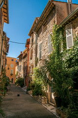 Alley view with stone houses and plants under sunny blue sky in Vence, a stunning medieval hamlet completely preserved. Located in the Alpes-Maritimes department, Provence region, southeastern France