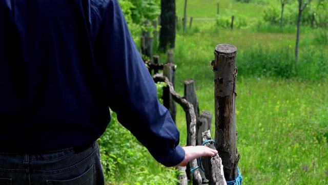 Man goes along old wooden fence - (4K)	