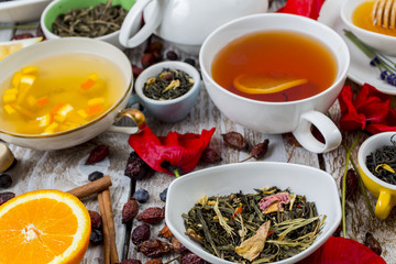 Various leaves of tea and spices on wooden background