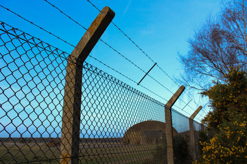 Barbed chainlink fence with a blue sky at the abandoned Air Force base of Rendlesham, UK