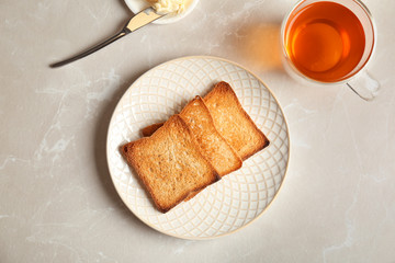 Plate with toasted bread and cup of tea on light background, top view