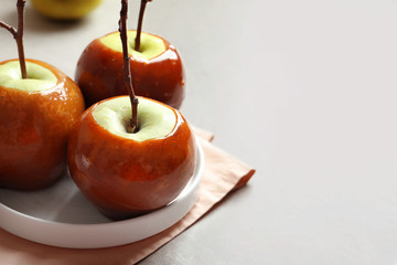 Plate with delicious green caramel apples on table