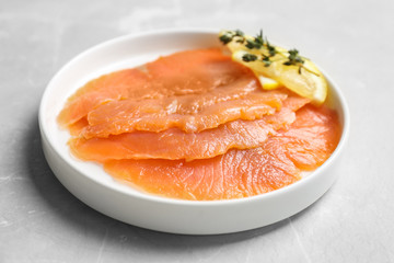 Plate with fresh sliced salmon fillet and lemon on table