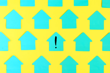 Empty brightly colored turquoise stickers in the shape of a house on a yellow background. In the...