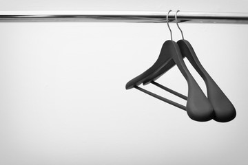 Obraz premium Clothes hangers on metal rail against light background