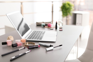 Makeup products for woman and laptop on table