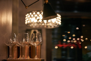 Empty wine glasses in restaurant with chandelier and lamp on background