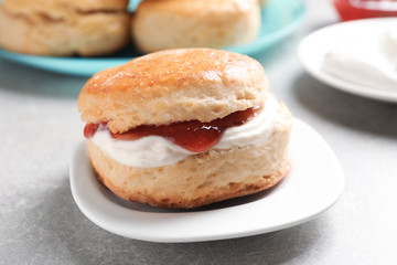 Fototapeta na wymiar Tasty scone with clotted cream and jam on plate, closeup