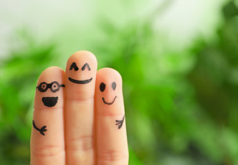 Fingers with drawings of happy faces against blurred background. Unity concept