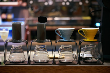 Coffee machine and glassware in coffee shop with bar shelves on background. Professional coffee maker in the restaurant interior 