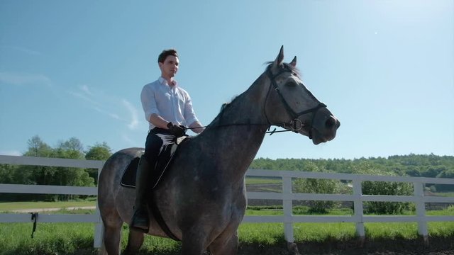 young man ride horse farm animal with blue sky in background. Slow motion