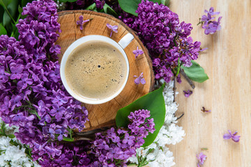 Obraz na płótnie Canvas spring background. coffee stands on a wooden hemp surrounded by lilac flowers