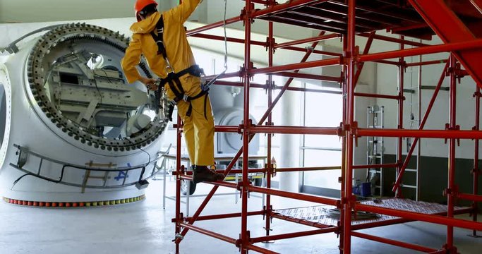 Male worker climbing scaffolding at solar station 