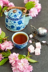 Tea concept, cups with tea and traditional teapot decorated with blooming spring tree branch 