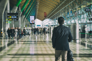 Close up of businessman carrying suitcase while walking through a passenger departure terminal in...