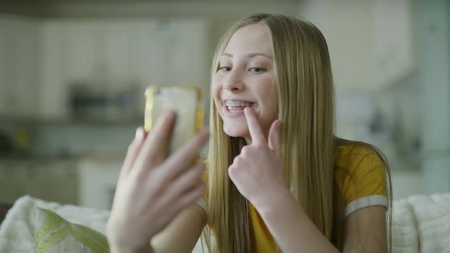 Slow motion of girl with braces video chatting on cell phone / Highland, Utah, United States