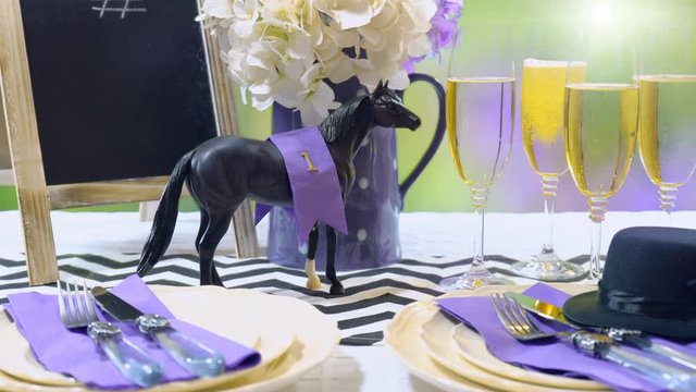 Horse Racing Day Luncheon fine dining table setting with small black fascinator hat, decorations and champagne, with lens flare.