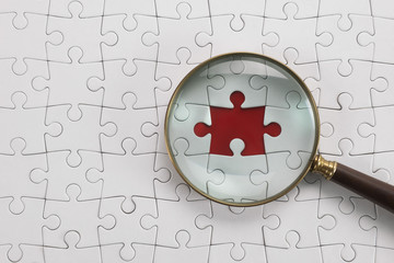 Magnifying glass searching missing puzzle peace 