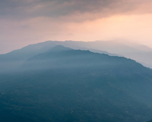 Fototapeta premium A view of Misty mountain ranges at the time of Sunrise.