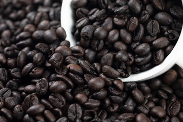 Roasted coffee beans in a white glass on background and texture