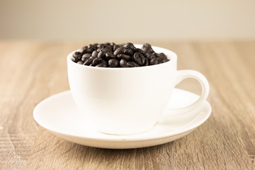 Roasted coffee beans in white glass on the wooden table
