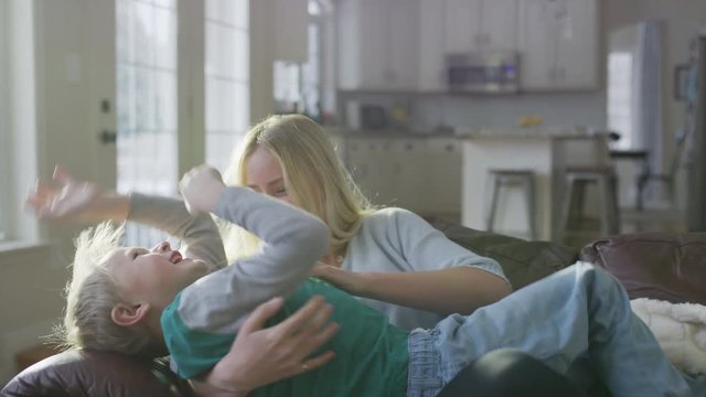 Playful girl carrying brother to sofa then tickling him / Highland, Utah, United States