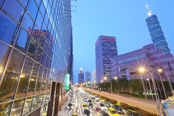 Panoramic view of a street corner in Downtown Taipei City with busy traffic trails at rush hour ~...