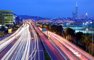 Fototapeta na wymiar Night scenery of Taipei City, with Taipei 101 Tower in XinYi District, downtown area with arch bridges and car trails on Dike Avenue ~ Romantic cityscape of Taipei at dusk by riverside (long exposure)