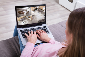 Woman Monitoring Home Security Cameras On Laptop