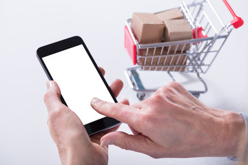 Cart Filled With Boxes And Hand Holding Mobile Phone