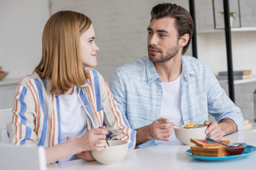 stylish couple sitting at table and having breakfast in kitchen