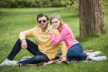 attractive young woman laying on shoulder of stylish boyfriend in sunglasses