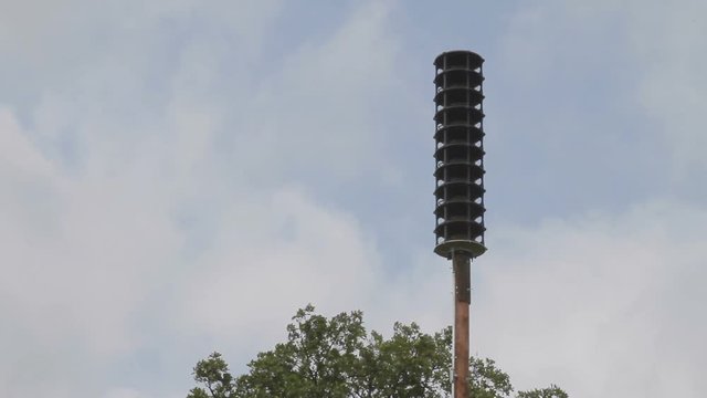 Tornado siren with fast moving clouds.
