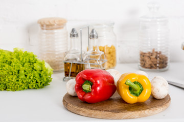 bell pepper, mushrooms and lettuce on wooden board in kitchen with jars