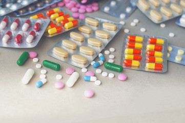 Pills and capsules on gray background.