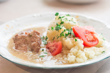 Polish traditional beef cutlets with sauce and potato and tomato slices. Beef cutlets knows in Poland as bitki wolowe.