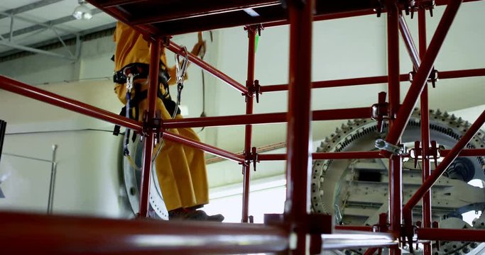 Male worker moving down from scaffolding at solar station 