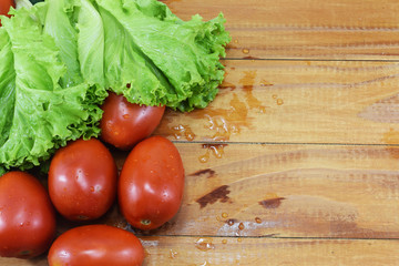 fresh juicy red tomatoes, cucumbers and lettuce on a wooden table