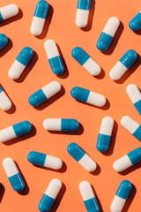top view of blue and white pills on orange surface