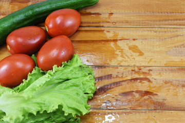 fresh juicy red tomatoes, cucumbers and lettuce on a wooden table