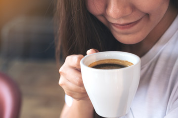 Closeup image of an Asian woman holding a coffee cup before drinking with feeling good in cafe