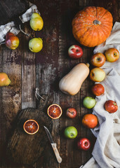 Fototapeta na wymiar top view of blood oranges, pears, apples, pumpkins, wooden board and knife on rustic wooden table