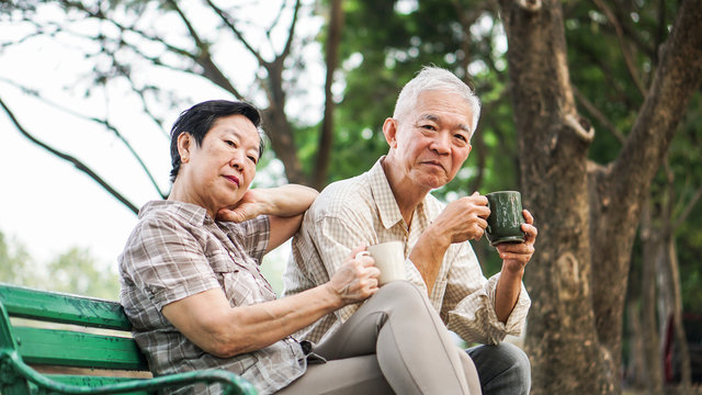 Asian Senior Couple Relax Drinking Coffee In Summer Park, Green Nature