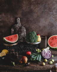 Fototapeta na wymiar cutting board, grater, scales, different fruits and vegetables on rustic wooden tabletop