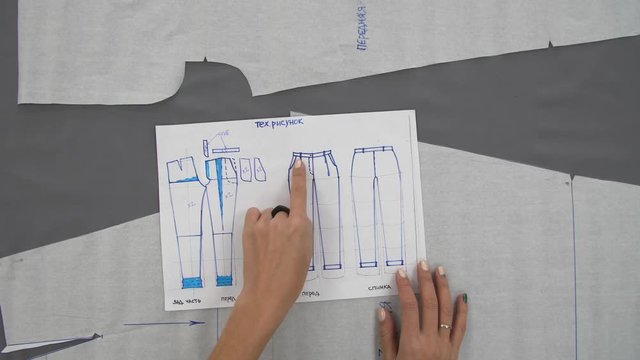 Female hands draw a blue ink scheme for sewing trousers