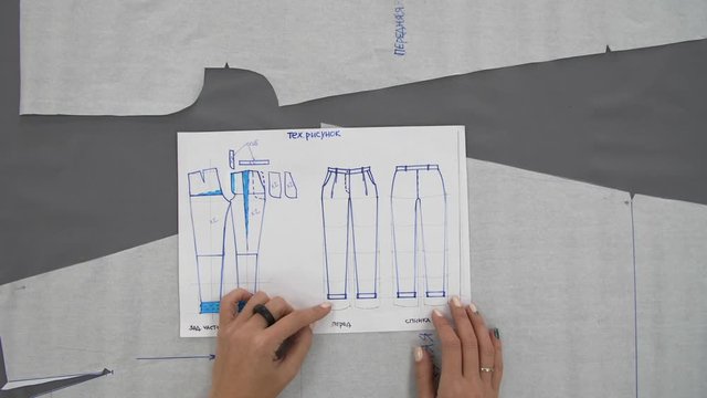 Training sewing trousers. Women's hands draw a scheme for sewing trousers